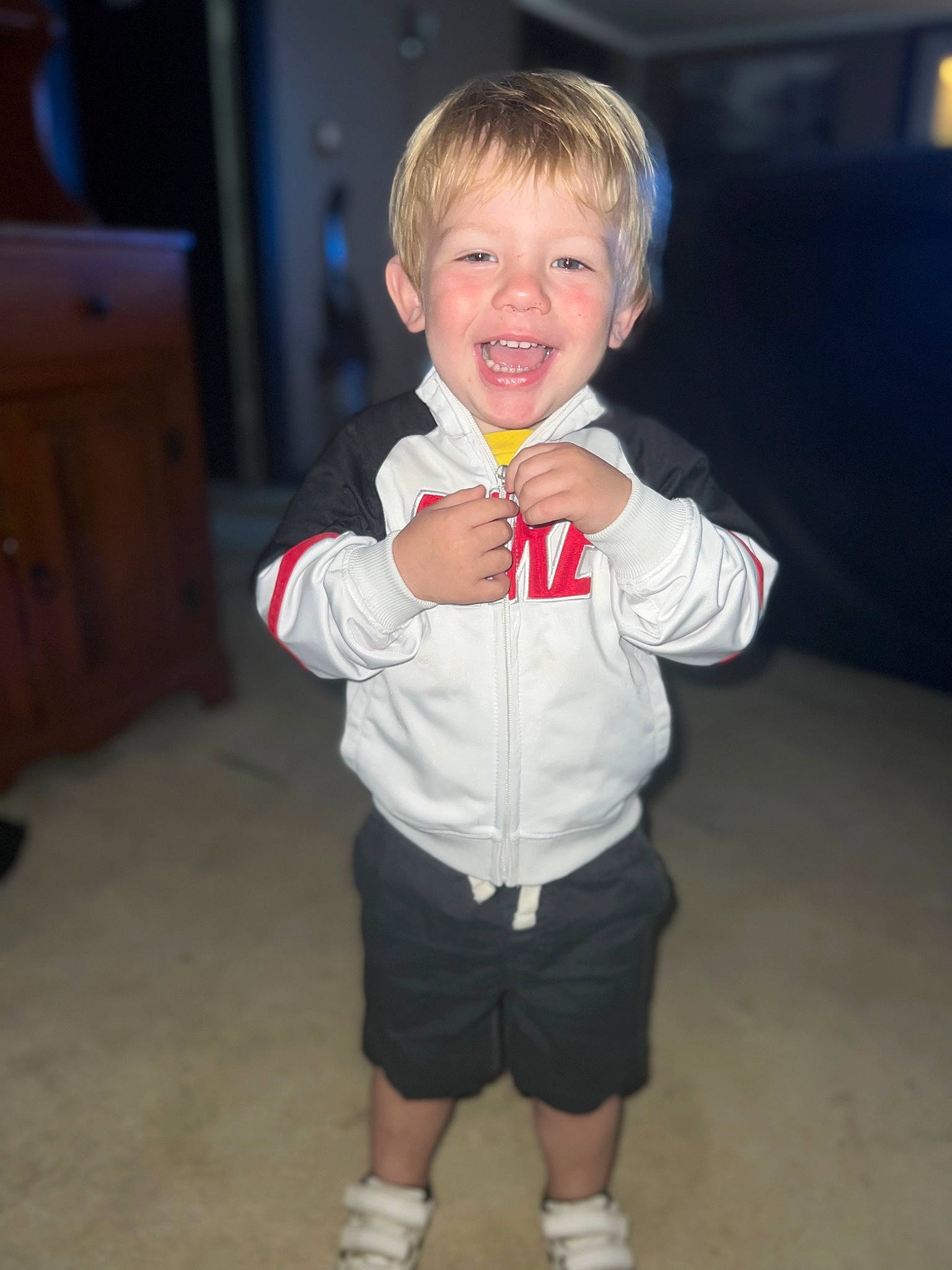 Donneghan is registered to the contest to win money with this photo: arm, baby_toddler_clothing, cabinetry, chest_of_drawers, child, chin, drawer, dresser, face, finger, flooring, fun, gesture, hand, head, person, shorts, sleeve, smile, thumb