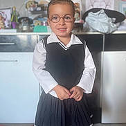 Serena a rejoint le concours — aidez-le/la à gagner de superbes lots ! child, glasses, smile, school_uniform, pleated_skirt, white_shirt, black_vest, indoor, home, floor, cabinet, clock, drawing, toy, person, portrait, standing, cute, happy, tights