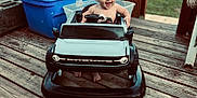 Raedynn joined the competition — help win amazing prizes! baby, baby_boy, blue_container, child, daylight, footwearless, fun, grass, happy, outdoor, person, plastic, playtime, seat, smiling, stairs, steering_wheel, toy_car, wood, wooden_deck