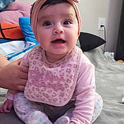 Celeste joined the competition — help win amazing prizes! baby, infant, child, sitting, bed, bedroom, pink_bow, headband, bib, long_sleeves, pants, smiling, wide_eyes, portrait, indoors, blanket, pillows, thermometer, breast_pump, caregiver_hand