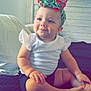 Autumn is registered to the contest to win money with this photo: baby, child, infant, headband, bow, white_shirt, black_shorts, sitting, smiling, indoors, window, quilted_bedspread, pillow, wooden_headboard, skin, face, hands, feet, natural_light, cute