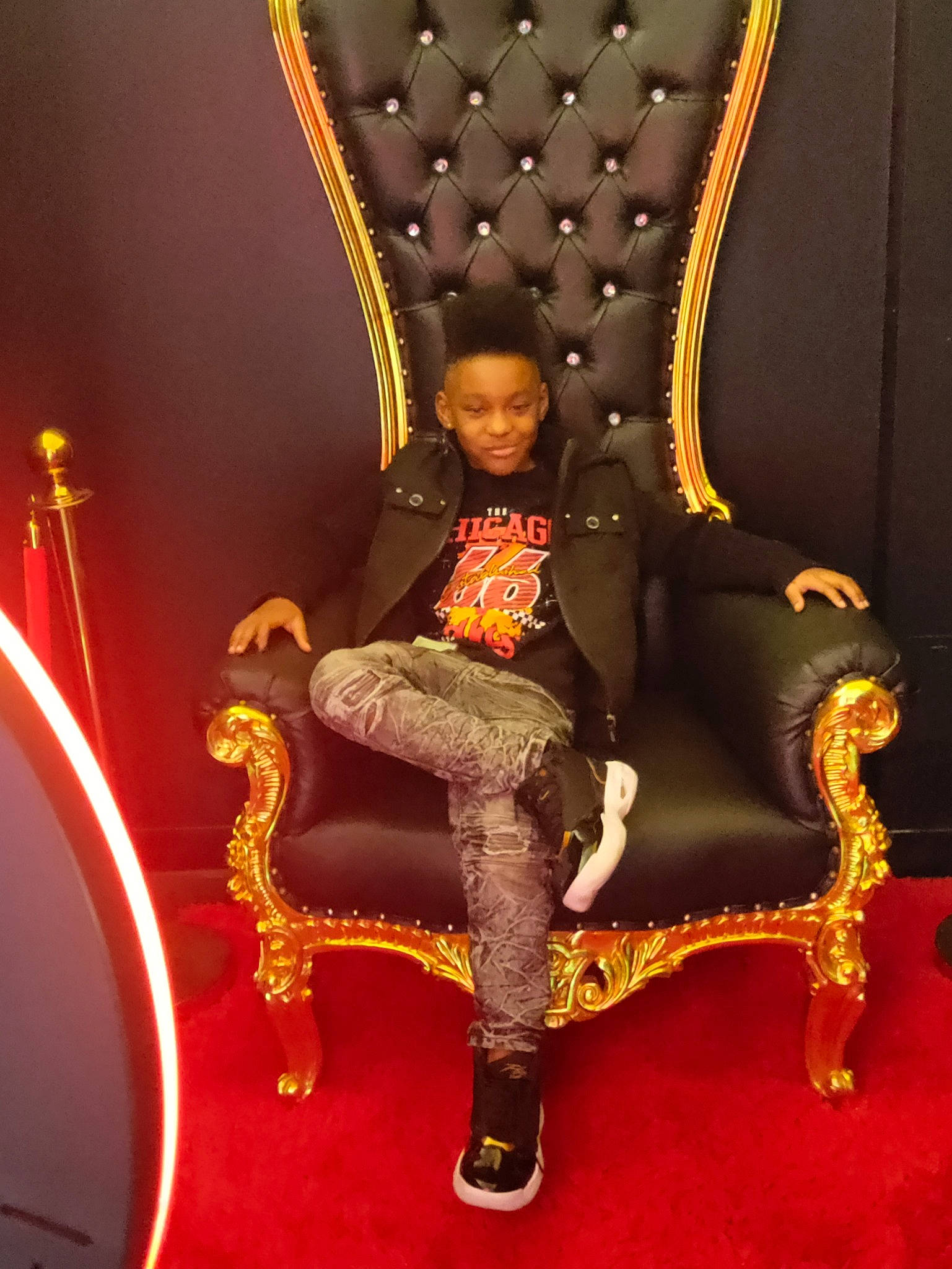 Ta'Kylen is registered to the contest to win money with this photo: carpet, chair, entertainment, event, fashion_design, flooring, fun, human_leg, joy, leisure, magenta, performance, performing_arts, person, room, sandal, sitting, thigh, tourist_attraction, wood