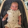 Joseph is registered to the contest to win money with this photo: baby, baby_carrier, child, clothing, comfort, cute, face, flowers, furniture, happy, home_decor, indoors, infant, living_room, person, seated, shirt, shorts, smiling, sofa