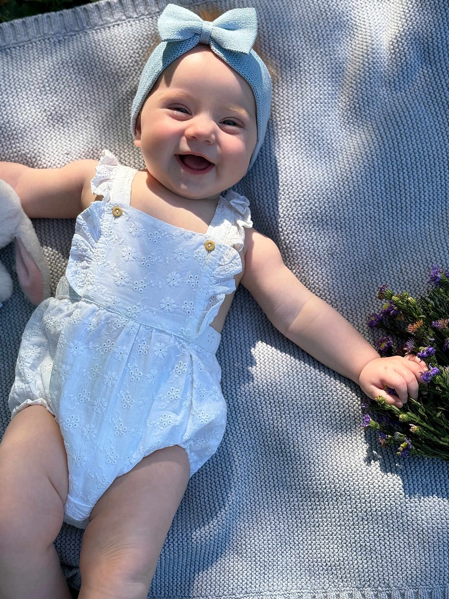 Vira joined the competition — help win amazing prizes! baby, smiling, headband, bow, romper, white_clothing, blanket, texture, flowers, purple_flowers, sunlight, shadow, happy, infant, cute, child, outdoor, nature, soft_light, portrait
