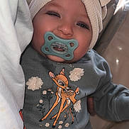 Evenly participe au concours pour gagner de l'argent avec cette photo : baby, child, pacifier, headband, bow, sweater, deer_print, clothing, cute, face, smiling, winking, indoors, person, portrait, baby_clothes, baby_accessory, cozy, closeup, infant