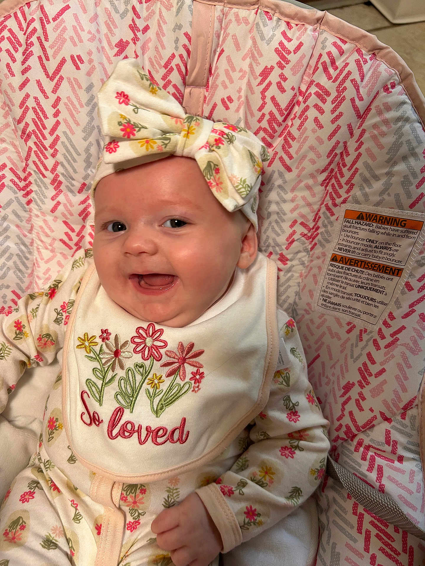 Aaliyah is registered to the contest to win money with this photo: baby, infant, smile, headband, floral, bib, clothing, pattern, seat, comfort, happy, cute, child, apparel, face, person, indoors, closeup, joy, adorable