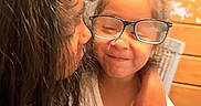 Maya is registered to the contest to win money with this photo: child, glasses, person, indoor, hug, affection, silly_face, long_hair, furniture, dresser, bottle, white_shirt, smile, portrait, casual, home, cute, happy, family, closeup