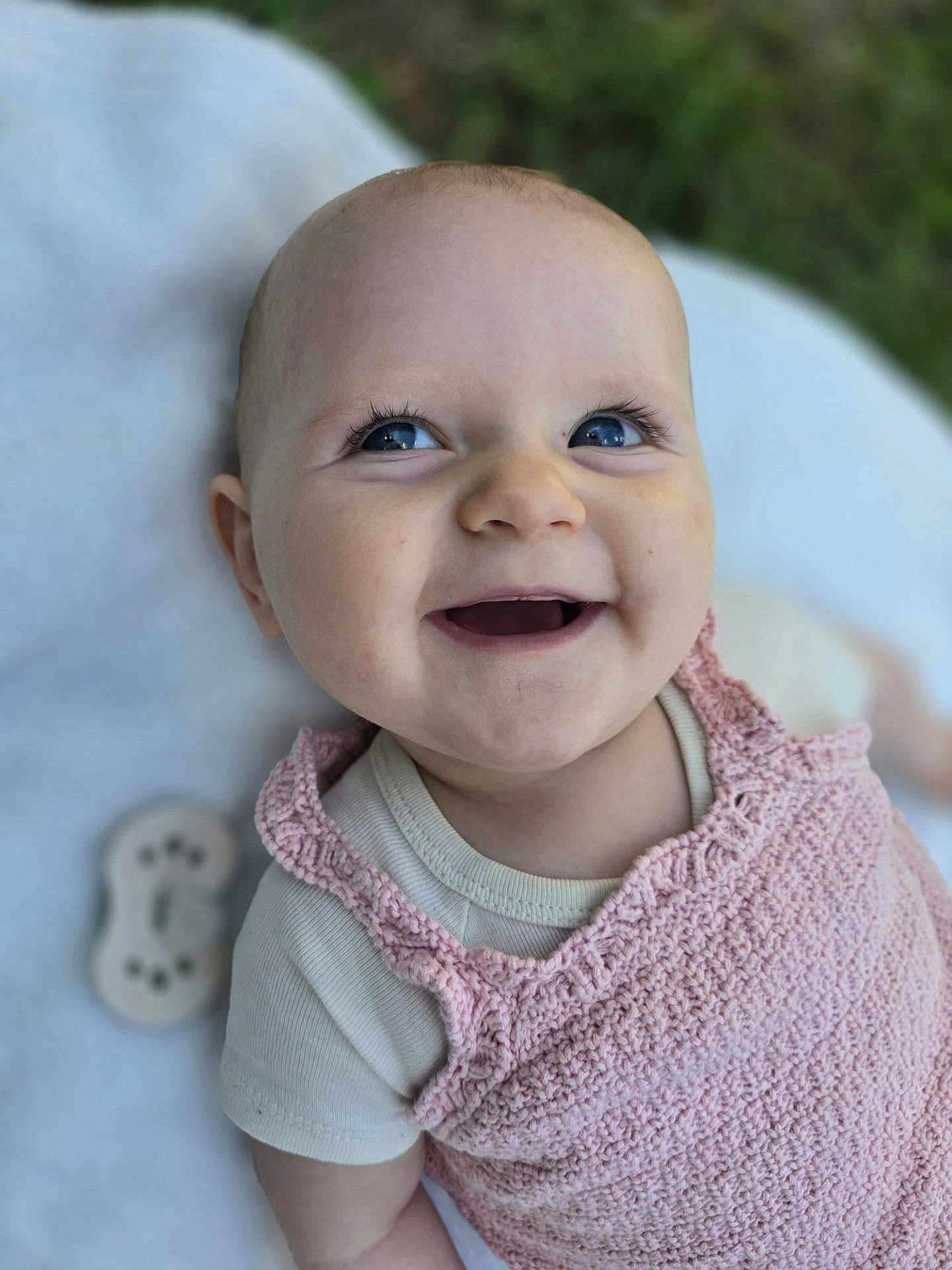 Eléanore participe au concours pour gagner de l'argent avec cette photo : baby, smiling, blue_eyes, pink_clothing, knitted, infant, happy, closeup, face, outdoor, blanket, cute, portrait, child, toddler, soft_texture, skin, person, natural_light, background_blur