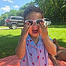 Romi joined the competition — help win amazing prizes! blanket, car, child, curly_hair, daylight, grass, happy, laughing, nature, outdoor, pajamas, park, person, playful, relaxing, smile, sunglasses, sunny, toddler, tree