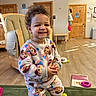 toddler, child, smiling, pajamas, indoor, wooden_floor, toy, furniture, happy, curly_hair, person, play, room, cozy, colorful, footwear, standing, young_child, cute, casual