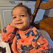 Romi joined the competition — help win amazing prizes! toddler, child, smiling, sweater, cartoon_characters, orange_clothing, earrings, hair_tie, kitchen, wooden_chair, high_chair, happy, face, portrait, indoor, food, table, cabinets, countertop, dishwasher