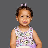 Romi is registered to the contest to win money with this photo: toddler, child, girl, curly_hair, pink_bow, necklace, dress, patterned_clothing, smile, portrait, studio_photo, innocence, cute, happy, young_child, fashion, accessory, isolated_background, colorful, person