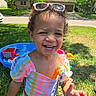 Romi joined the competition — help win amazing prizes! toddler, child, smiling, curly_hair, sunglasses, colorful_clothing, toy_giraffe, outdoor, grass, sunny, pool, playtime, happy, summer, backyard, person, cute, portrait, daylight, fun