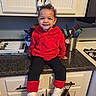 Romi is registered to the contest to win money with this photo: toddler, child, smiling, red_hoodie, white_bow, curly_hair, white_sneakers, kitchen_counter, kitchen_utensils, cabinet, cutlery_tray, happy, indoor, person, furniture, black_pants, appliance, home, portrait, casual_clothing