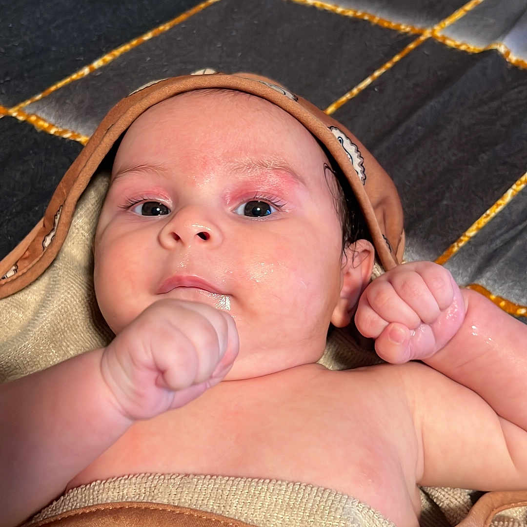Sandiel joined the competition — help win amazing prizes! baby, infant, towel, wrapped, hood, fist, curious, relaxed, skin, lying_down, indoors, texture, pattern, face, closeup, child, newborn, cute, portrait, person