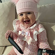 Aria Ella joined the competition — help win amazing prizes! baby, child, smiling, pink_hat, pom_poms, frilly_outfit, remote_control, couch, indoors, cute, happy, sitting, white_socks, tulle, portrait, person, infant, toy, playful, home