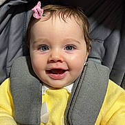 Everleigh is registered to the contest to win money with this photo: baby, smiling, blue_eyes, pink_bow, car_seat, yellow_sweater, blanket, pacifier_clip, beads, child, happy, infant, face, clothing, indoor, cute, young_child, person, portrait, seatbelt
