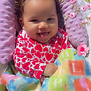 Taylor joined the competition — help win amazing prizes! baby, infant, smiling, tongue_out, blanket, alphabet, heart_pattern, clothing, purple_cushion, outdoor, grass, flower_stickers, cute, happy, child, person, portrait, colorful, playful, cozy