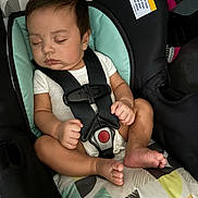 Jahkai is registered to the contest to win money with this photo: baby, sleeping, car_seat, child, infant, straps, seatbelt, cushion, patterned_fabric, white_clothing, peaceful, closed_eyes, small_hands, small_feet, indoors, safety, rest, cute, comfort, person