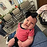 baby, infant, child, polka_dot, pink_clothing, black_bow, sitting, lap, waiting_room, chairs, floor, jeans, person, indoor, framed_photos, plants, car_seat, casual_clothing, smiling, cute