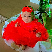 Kenza a rejoint le concours — aidez-le/la à gagner de superbes lots ! baby, baby_shoes, celebration, child, christmas_tree, cute, decorations, festive, floor, flooring, green_lights, headband, holiday, holiday_season, indoors, infant, portrait, red_dress, sitting, tree_skirt