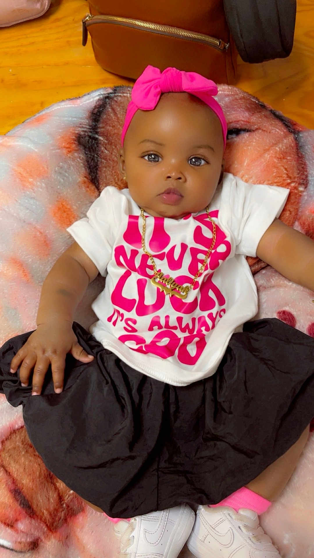 Aaliyah is registered to the contest to win money with this photo: baby, child, infant, headband, pink, white_shoes, black_skirt, gold_necklace, shirt, blanket, sitting, indoor, cute, fashion, footwear, person, portrait, accessory, floor, bag