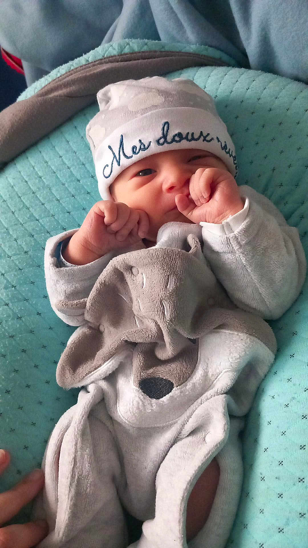 émilio participe au concours pour gagner de l'argent avec cette photo : baby, infant, blanket, hat, clothing, face, hand, cushion, quilted, sleepwear, newborn, person, cute, soft, resting, cozy, indoors, portrait, toddler, sleep