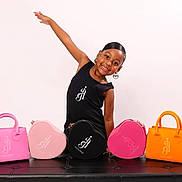 Alaiya joined the competition — help win amazing prizes! child, girl, smile, pose, handbags, pink, orange, black, heart_shaped, studio, portrait, fashion, accessories, earrings, black_dress, bench, happy, young, cute, colorful