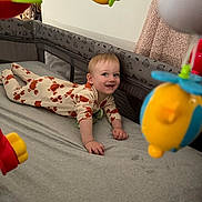 Lucas joined the competition — help win amazing prizes! baby, crib, pajamas, toy, smiling, tummy_time, indoor, child, hanging_toy, blanket, clothing, face, person, bed, play, happy, infant, room, colorful, cute