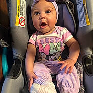 Emerald is registered to the contest to win money with this photo: baby, car_seat, infant, purple_clothing, headband, socks, cute, surprised_expression, child, seatbelt, warning_label, indoor, person, apparel, toddler, child_seat, plush, pink, cartoon_characters, smile