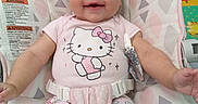 Emerald is registered to the contest to win money with this photo: baby, infant, smile, headband, hello_kitty, onesie, patterned_pants, baby_chair, seatbelt, happy, child, cute, indoor, person, clothing, toddler, pink, pastel_colors, face, expression