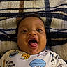 baby, infant, smiling, happy, onesie, cartoon, blanket, striped, face, expression, mouth_open, cute, child, lying_down, indoors, person, young, playful, clothing, pattern