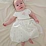 baby, infant, smiling, white_dress, bird_pattern, lying_down, blanket, soft_lighting, cute, child, happy, portrait, skin, head, hands, feet, indoors, toddler, person, clothing
