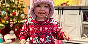 Alexis-Mai joined the competition — help win amazing prizes! toddler, child, hat, bear_hat, pajamas, mickey_mouse, cookie, smiling, indoor, rug, carpet, christmas_tree, holiday, decorations, living_room, furniture, television, toy, floor, person
