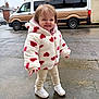 child, cloudy_weather, cute, fun, happy, hearts, hoodie, jacket, outdoor, pants, person, residential_area, sidewalk, smile, standing, toddler, van, vehicle, wet_pavement, white_shoes