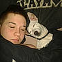 person, dog, sleeping, bed, blanket, pillow, indoor, resting, closeup, cozy, relaxation, pet, companion, black_blanket, white_dog, short_hair, collar, eyebrow_piercing, face, comfort