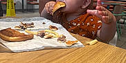 Serenity joined the competition — help win amazing prizes! toddler, child, burger, food, table, restaurant, fast_food, fries, eating, brown_hair, curious, indoor, clothing, high_chair, paper_wrap, hand, face, mouth, seat, casual