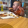 Serenity joined the competition — help win amazing prizes! toddler, child, burger, food, fast_food, table, high_chair, fries, meal, restaurant, casual, messy, eating, hand, clothing, indoor, face, side_view, happy, young