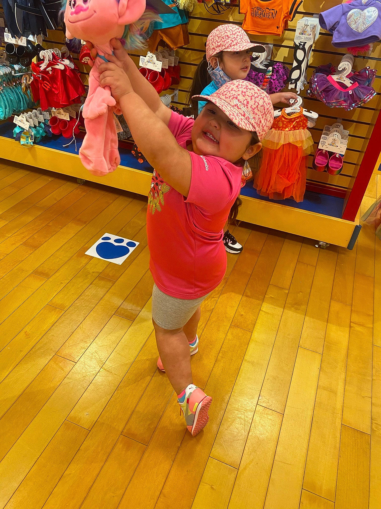Mackenzie is registered to the contest to win money with this photo: child, entertainment, event, floor, flooring, fun, happy, hardwood, hat, headwear, human_leg, leisure, orange, party_supply, person, pink, shoe, shorts, sneakers, sportswear