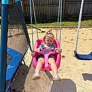 Everly is registered to the contest to win money with this photo: blue, child, fence, footwear, grass, hairclip, happy, outdoor, person, pink, play, playground, rope, sand, summer, sunlight, swing, toddler, toy, trampoline