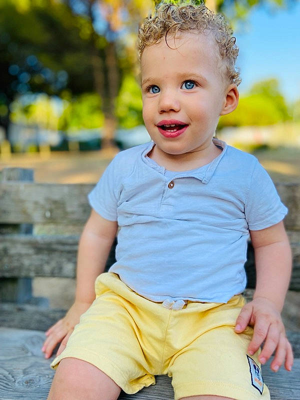 Thylio participe au concours pour gagner de l'argent avec cette photo : baby_toddler_clothing, cheek, chin, eye, face, flash_photography, grass, hairstyle, happy, head, neck, orange, person, photograph, shorts, skin, sleeve, smile, standing, toddler