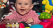 Kodi Sue is registered to the contest to win money with this photo: activity_center, baby, blue, bright, child, colorful, cute, face, furniture, happy, head, indoor, infant, person, pink_clothing, plastic, play, smiling, toy, yellow