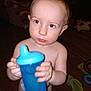 Duwane joined the competition — help win amazing prizes! toddler, child, blue_sippy_cup, indoor, floor, toy, slippers, bare_chest, diaper, curious, young_child, person, holding, looking_away, home, wooden_floor, plastic_cup, expression, standing, baby