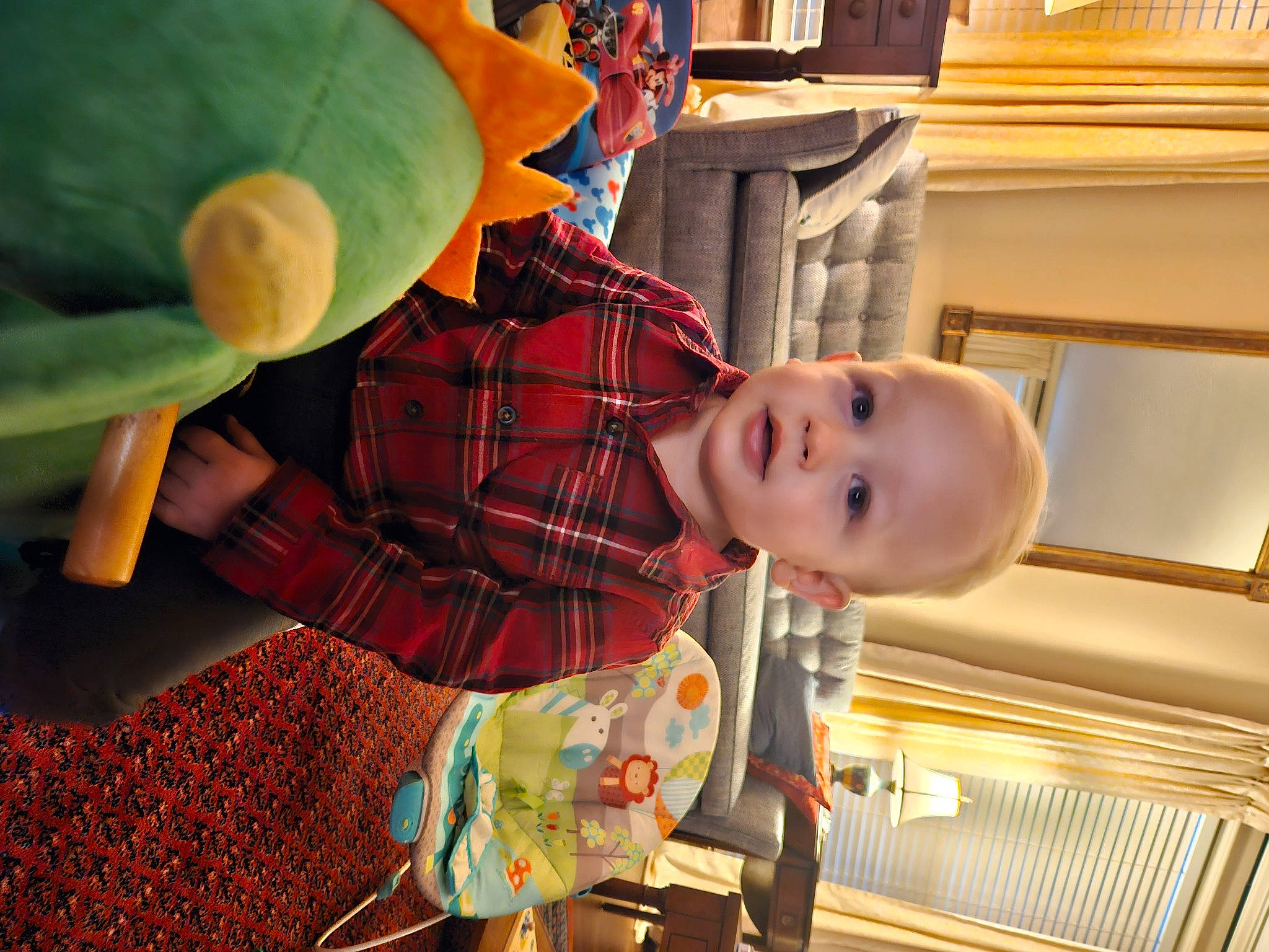 Austin is registered to the contest to win money with this photo: baby, baby_products, baby_toddler_clothing, child, comfort, flooring, fun, happy, orange, pattern, person, plaid, play, room, sitting, smile, tartan, toddler, toy, visual_arts