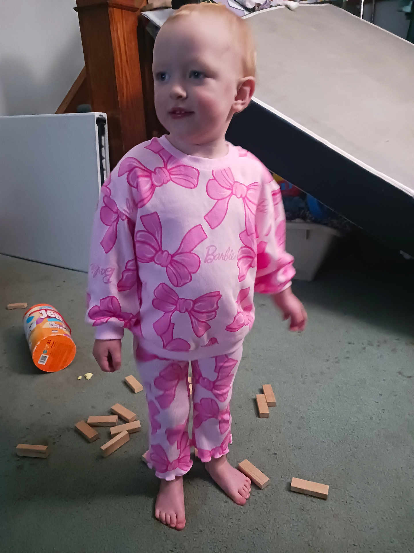 Riley Rose is registered to the contest to win money with this photo: toddler, child, pink_clothing, barefoot, wooden_blocks, carpet, indoor, toy_container, curious_expression, standing, playtime, casual, young_child, floor, home, person, long_sleeves, pants, light_skin, short_hair