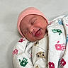newborn, baby, infant, sleeping, smiling, pink_hat, swaddled, blanket, portrait, face, indoors, hospital, bedding, clothing, cute, cozy, close_up, happy, patterned_fabric, photography