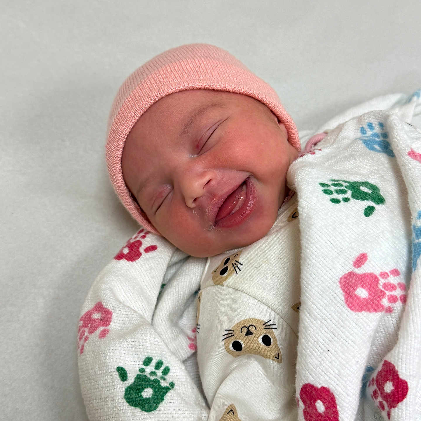 Nevaeh is registered to the contest to win money with this photo: newborn, baby, infant, sleeping, smiling, pink_hat, swaddled, blanket, portrait, face, indoors, hospital, bedding, clothing, cute, cozy, close_up, happy, patterned_fabric, photography