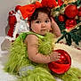 baby, celebration, child, christmas, christmas_tree, curly_hair, cute, decorations, festive, fluffy_clothing, green_outfit, holiday, holiday_decor, holiday_spirit, indoor, ornament, portrait, red_bow, sitting, smiling