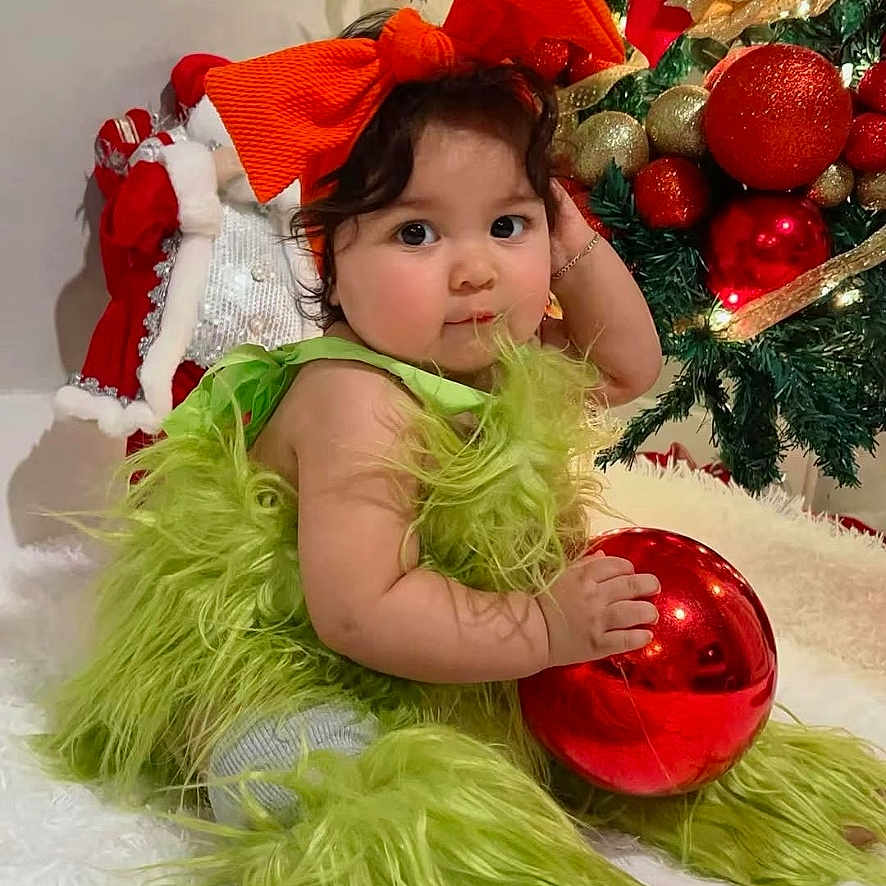 Victoria Sopfia joined the competition — help win amazing prizes! baby, celebration, child, christmas, christmas_tree, curly_hair, cute, decorations, festive, fluffy_clothing, green_outfit, holiday, holiday_decor, holiday_spirit, indoor, ornament, portrait, red_bow, sitting, smiling