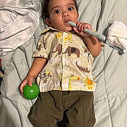 Kayden is registered to the contest to win money with this photo: toddler, child, baby, bed, blanket, green_ball, teething_toy, animal_print_shirt, pants, diaper, lying_down, indoors, cute, wide_eyes, handheld_object, soft_surface, casual_clothing, portrait, infant, playful